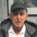 An older man wearing a green hat and a plaid jacket.