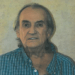 A portrait of an older man in a plaid shirt.